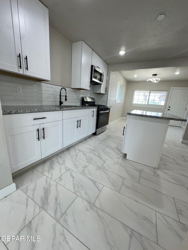 7216 Amethyst Rd, El Paso, TX 79915 - kitchen featuring appliances with stainless steel finishes, light marble finish flooring, dark stone counters, white cabinets, and recessed lighting