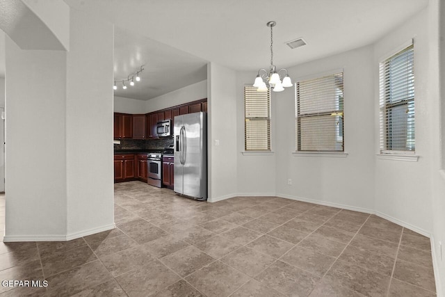 5020 Copper Ranch Ave, El Paso, TX 79934 - kitchen with appliances with stainless steel finishes, a chandelier, backsplash, dark brown cabinets, and pendant lighting
