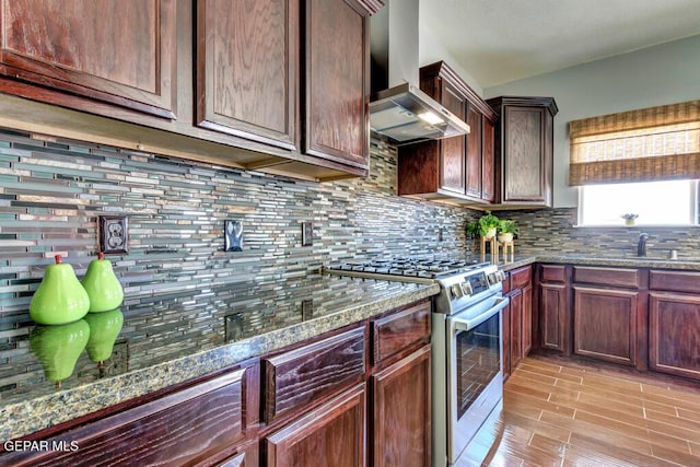 545 Lanner Dr, El Paso, TX 79928 - kitchen with gas stove, wall chimney exhaust hood, backsplash, and dark stone countertops