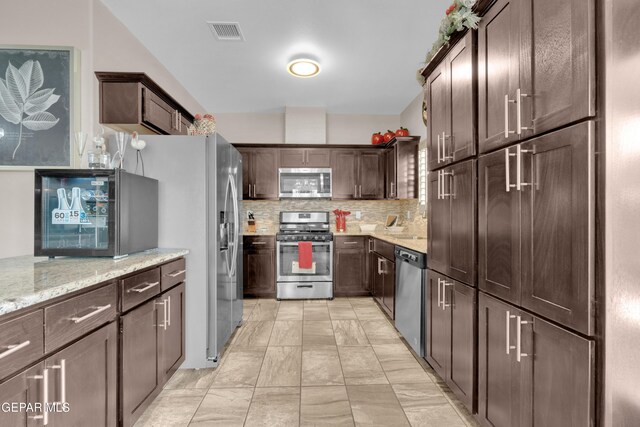 14192 Earl Chokiski, El Paso, TX 79938 - kitchen featuring stainless steel appliances, tasteful backsplash, dark brown cabinets, and light stone countertops
