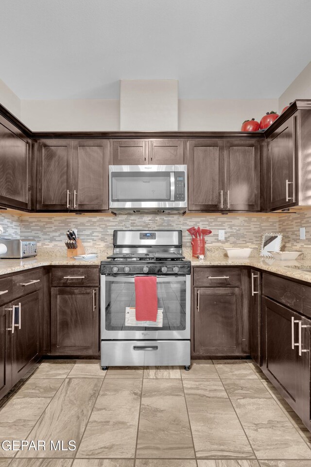 14192 Earl Chokiski, El Paso, TX 79938 - kitchen with stainless steel appliances, dark brown cabinets, tasteful backsplash, and light stone countertops