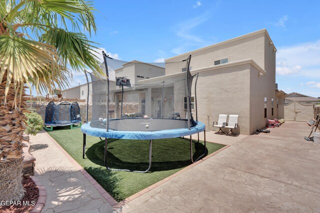 14192 Earl Chokiski, El Paso, TX 79938 - back of property with a trampoline, stucco siding, a patio, and a lawn