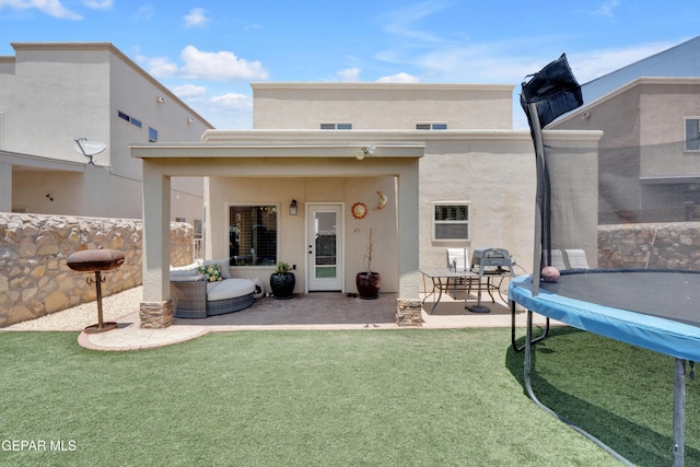 14192 Earl Chokiski, El Paso, TX 79938 - rear view of house featuring a trampoline, a patio, stucco siding, and a lawn