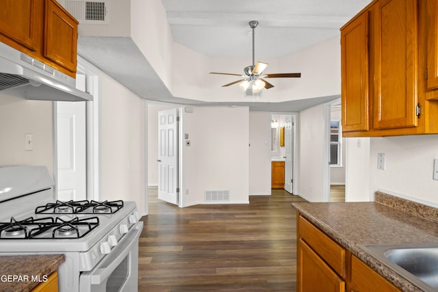 10980 Northampton St, El Paso, TX 79934 - kitchen featuring white range with gas stovetop, a ceiling fan, dark countertops, dark wood-type flooring, and brown cabinetry