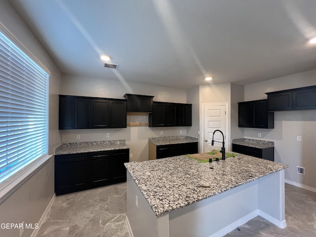 3720 Hill Top Place, El Paso, TX 79938 - kitchen with light marble finish flooring, an island with sink, light stone counters, plenty of natural light, and recessed lighting