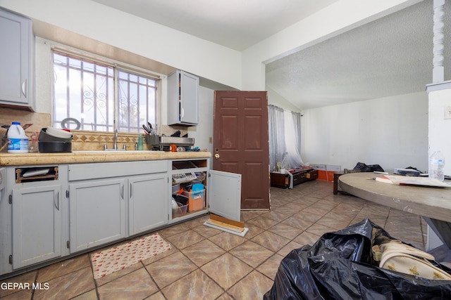 123 Marquita Ln, El Paso, TX 79915 - kitchen featuring open floor plan, light countertops, decorative backsplash, lofted ceiling, and light tile patterned floors