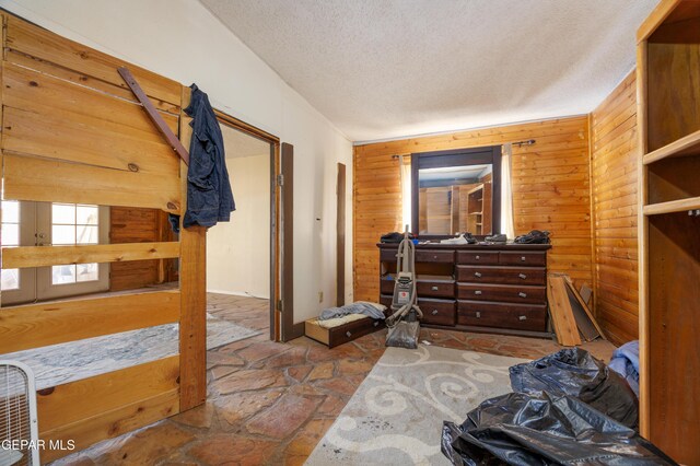 123 Marquita Ln, El Paso, TX 79915 - bedroom with stone finish floors, a textured ceiling, and wood walls