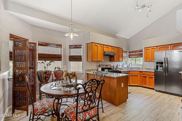 700 Milton Henry Ave, El Paso, TX 79932 - kitchen with stainless steel appliances, brown cabinetry, under cabinet range hood, a peninsula, and high vaulted ceiling
