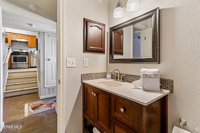 700 Milton Henry Ave, El Paso, TX 79932 - bathroom featuring a textured wall, vanity, a textured ceiling, decorative backsplash, and tile patterned floors