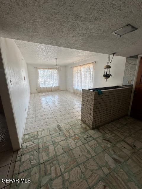 7190 Fatima Ave, El Paso, TX 79915 - unfurnished living room with a textured ceiling and a chandelier