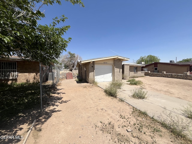 8725 Clavel Dr, El Paso, TX 79907 - view of property exterior featuring dirt driveway, brick siding, and an attached garage