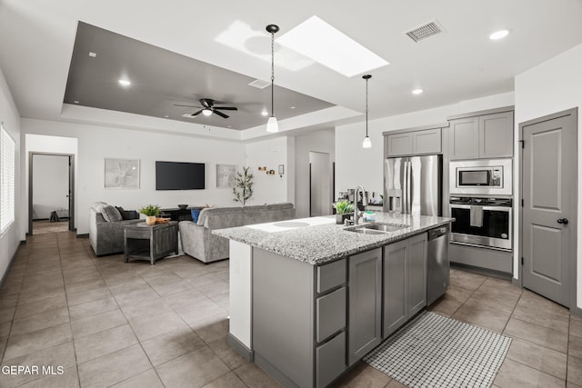 13699 Kathys Ct, El Paso, TX 79928 - kitchen with stainless steel appliances, gray cabinets, a raised ceiling, a skylight, and light stone counters