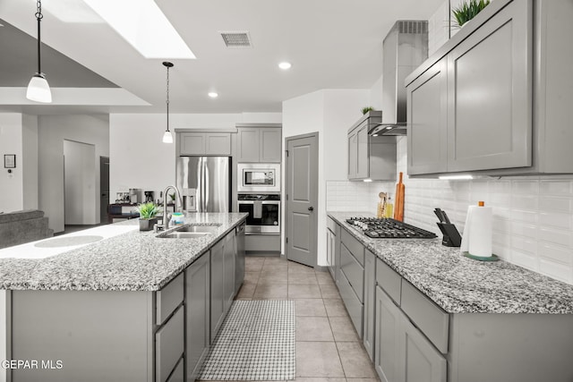 13699 Kathys Ct, El Paso, TX 79928 - kitchen featuring appliances with stainless steel finishes, gray cabinetry, decorative backsplash, wall chimney exhaust hood, and light stone counters