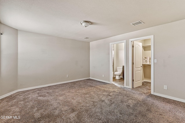 5465 Limestone Dr, El Paso, TX 79934 - unfurnished bedroom with carpet floors, connected bathroom, a spacious closet, and a textured ceiling
