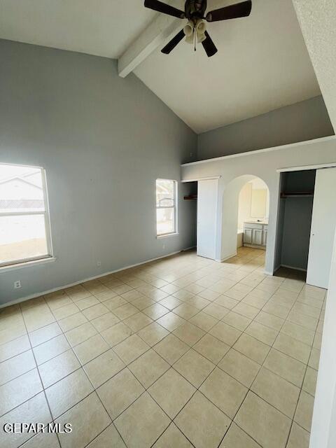 10940 Golden Pond Dr, El Paso, TX 79934 - unfurnished bedroom featuring arched walkways, high vaulted ceiling, beam ceiling, light tile patterned flooring, and a ceiling fan
