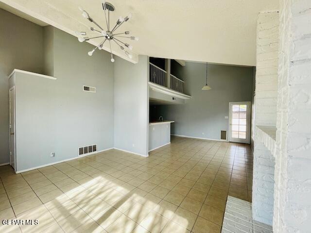 10940 Golden Pond Dr, El Paso, TX 79934 - unfurnished living room featuring a chandelier, light tile patterned flooring, and a towering ceiling