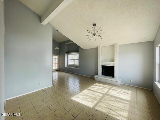 10940 Golden Pond Dr, El Paso, TX 79934 - unfurnished living room featuring tile patterned flooring, a chandelier, beamed ceiling, a brick fireplace, and high vaulted ceiling