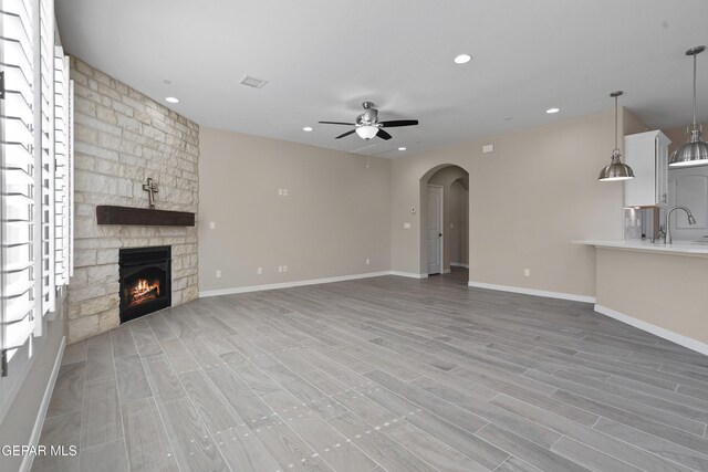 912 Malven Pl, El Paso, TX 79928 - unfurnished living room featuring ceiling fan, a fireplace, light wood-style flooring, arched walkways, and recessed lighting