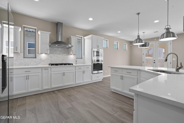 912 Malven Pl, El Paso, TX 79928 - kitchen with wall chimney exhaust hood, stainless steel appliances, white cabinetry, light countertops, and tasteful backsplash