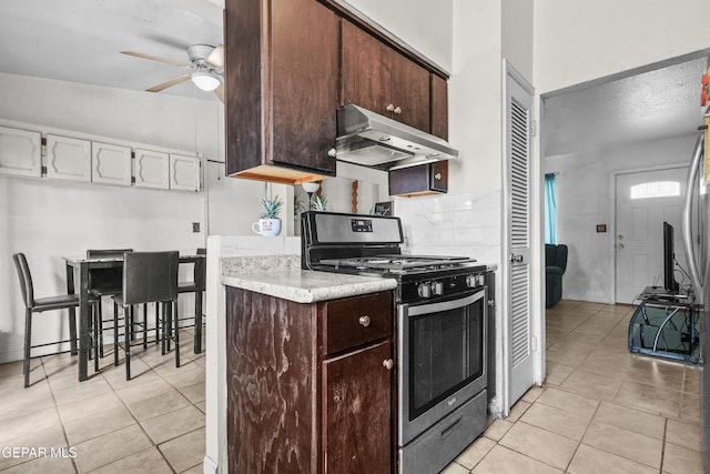5828 Blackhawk Dr, El Paso, TX 79924 - kitchen featuring stainless steel gas range, under cabinet range hood, a ceiling fan, light tile patterned floors, and light countertops