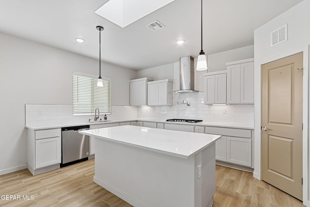 248 Farnborough St, El Paso, TX 79928 - kitchen with stainless steel dishwasher, wall chimney exhaust hood, a skylight, decorative backsplash, and light wood-type flooring