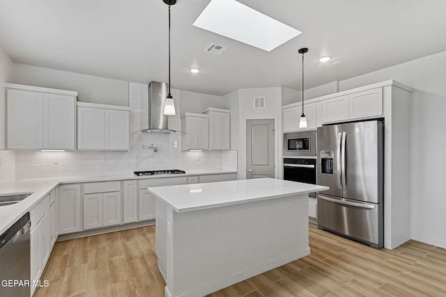 248 Farnborough St, El Paso, TX 79928 - kitchen featuring stainless steel appliances, wall chimney exhaust hood, a skylight, light wood finished floors, and backsplash