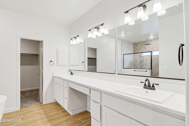 248 Farnborough St, El Paso, TX 79928 - bathroom with a walk in closet, a stall shower, wood finished floors, and double vanity