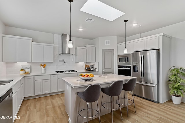 248 Farnborough St, El Paso, TX 79928 - kitchen with stainless steel appliances, wall chimney range hood, a skylight, light wood-style floors, and light countertops