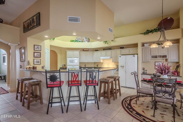 6316 Franklin Red Dr, El Paso, TX 79912 - kitchen with white appliances, a high ceiling, a breakfast bar area, dark countertops, and light tile patterned floors