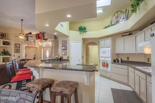 6316 Franklin Red Dr, El Paso, TX 79912 - kitchen with white appliances, arched walkways, a breakfast bar area, dark stone counters, and recessed lighting