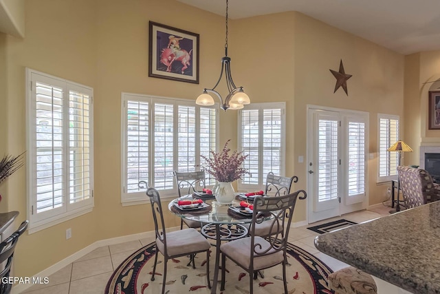 6316 Franklin Red Dr, El Paso, TX 79912 - dining room with light tile patterned floors, a high ceiling, a chandelier, and a glass covered fireplace