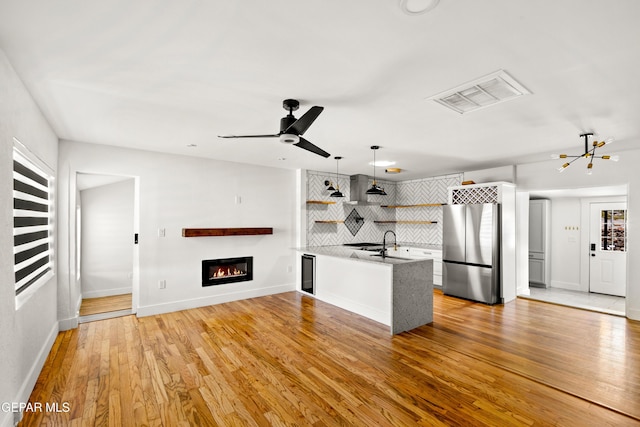 721 Mesita Dr, El Paso, TX 79902 - kitchen featuring open shelves, freestanding refrigerator, decorative backsplash, wine cooler, and a glass covered fireplace