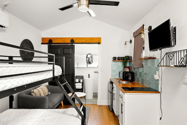 721 Mesita Dr, El Paso, TX 79902 - bedroom with vaulted ceiling, light wood-type flooring, bar, a wall unit AC, and freestanding refrigerator