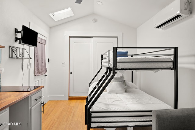 721 Mesita Dr, El Paso, TX 79902 - bedroom featuring a wall mounted air conditioner, a skylight, lofted ceiling, and light wood-type flooring
