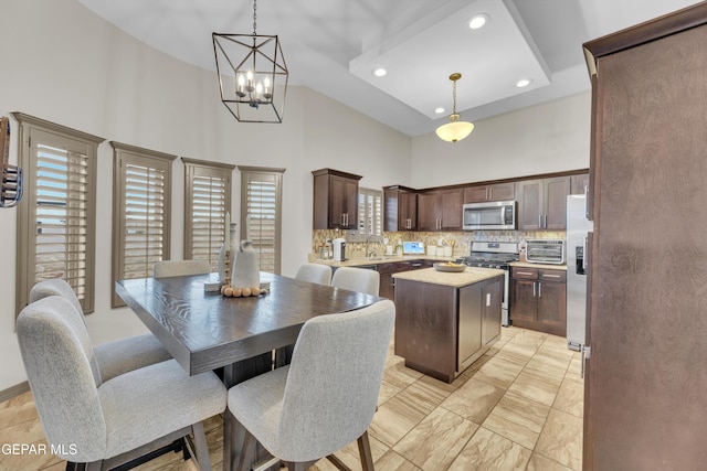 7817 Enchanted Trail Dr, El Paso, TX 79911 - kitchen featuring appliances with stainless steel finishes, a high ceiling, a center island, dark brown cabinets, and a chandelier