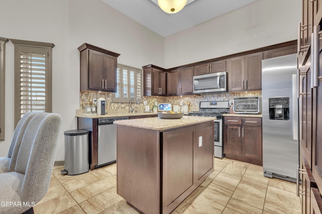 7817 Enchanted Trail Dr, El Paso, TX 79911 - kitchen featuring appliances with stainless steel finishes, tasteful backsplash, dark brown cabinetry, and a center island