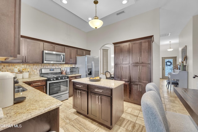 7817 Enchanted Trail Dr, El Paso, TX 79911 - kitchen with stainless steel appliances, arched walkways, pendant lighting, decorative backsplash, and a center island