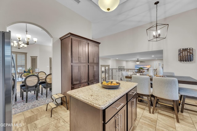 7817 Enchanted Trail Dr, El Paso, TX 79911 - kitchen with a chandelier, stainless steel fridge, light stone counters, a kitchen island, and a towering ceiling
