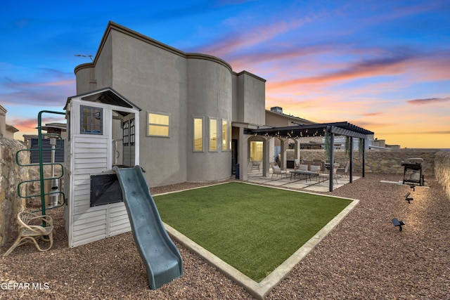 7817 Enchanted Trail Dr, El Paso, TX 79911 - back of house at dusk featuring a pergola, a patio area, stucco siding, and a yard