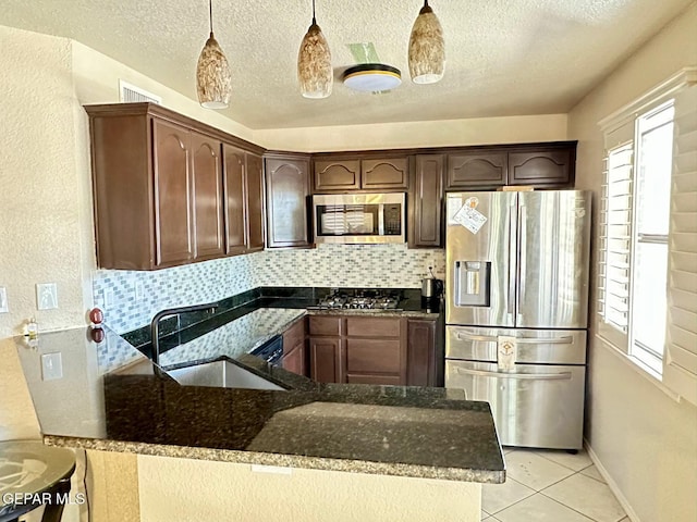 11713 Queens Garden Cir, El Paso, TX 79936 - kitchen with appliances with stainless steel finishes, dark stone countertops, decorative backsplash, a peninsula, and a textured ceiling