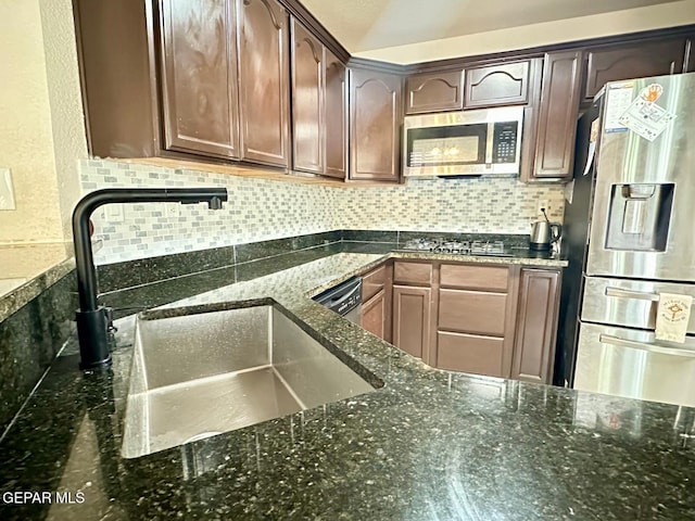 11713 Queens Garden Cir, El Paso, TX 79936 - kitchen featuring appliances with stainless steel finishes, dark stone counters, decorative backsplash, and dark brown cabinetry