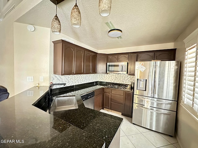 11713 Queens Garden Cir, El Paso, TX 79936 - kitchen with appliances with stainless steel finishes, dark stone counters, backsplash, a peninsula, and dark brown cabinetry