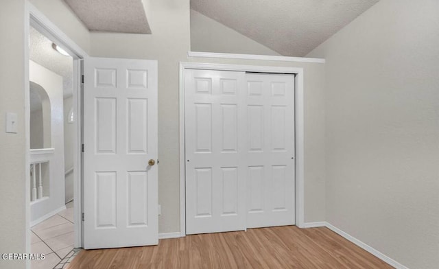 11713 Queens Garden Cir, El Paso, TX 79936 - unfurnished bedroom featuring lofted ceiling, light wood finished floors, a textured ceiling, and a closet