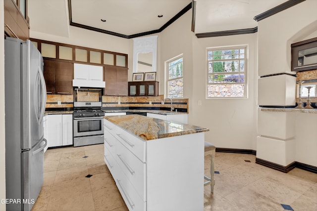 4540 N Stanton St, El Paso, TX 79902 - kitchen featuring stainless steel appliances, crown molding, under cabinet range hood, tasteful backsplash, and a kitchen island