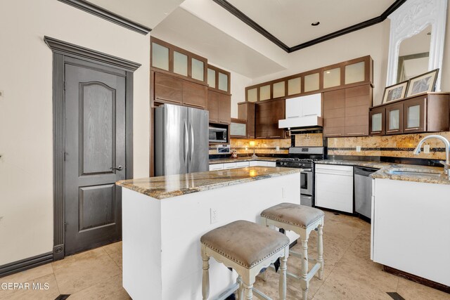 4540 N Stanton St, El Paso, TX 79902 - kitchen featuring stainless steel appliances, under cabinet range hood, ornamental molding, tasteful backsplash, and a kitchen island