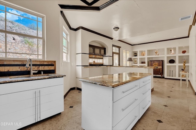 4540 N Stanton St, El Paso, TX 79902 - kitchen featuring ornamental molding, a kitchen island, stone counters, white cabinets, and tasteful backsplash