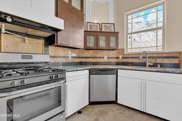 4540 N Stanton St, El Paso, TX 79902 - kitchen with appliances with stainless steel finishes, ventilation hood, backsplash, glass insert cabinets, and dark countertops