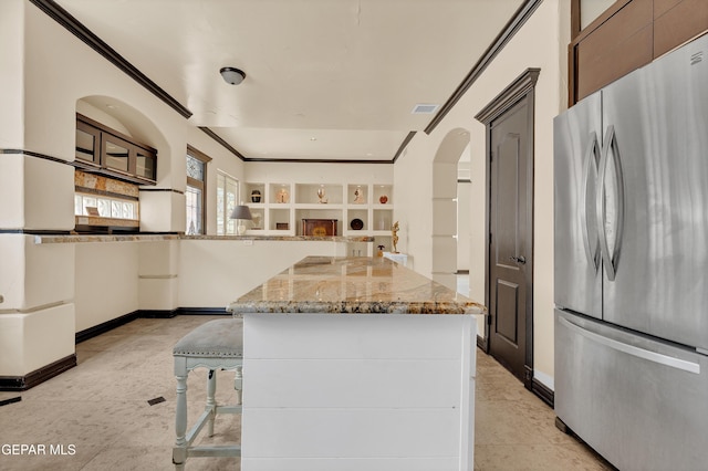 4540 N Stanton St, El Paso, TX 79902 - kitchen featuring freestanding refrigerator, ornamental molding, light stone countertops, open floor plan, and arched walkways
