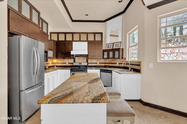 4540 N Stanton St, El Paso, TX 79902 - kitchen with appliances with stainless steel finishes, crown molding, a kitchen island, backsplash, and light stone counters