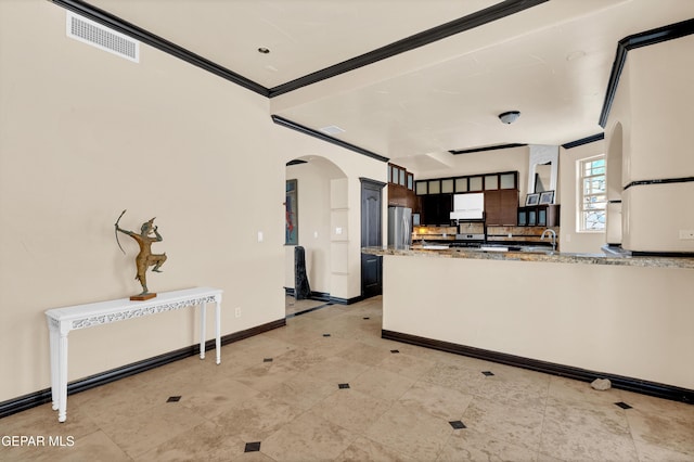 4540 N Stanton St, El Paso, TX 79902 - kitchen with arched walkways, freestanding refrigerator, a peninsula, light stone countertops, and ornamental molding